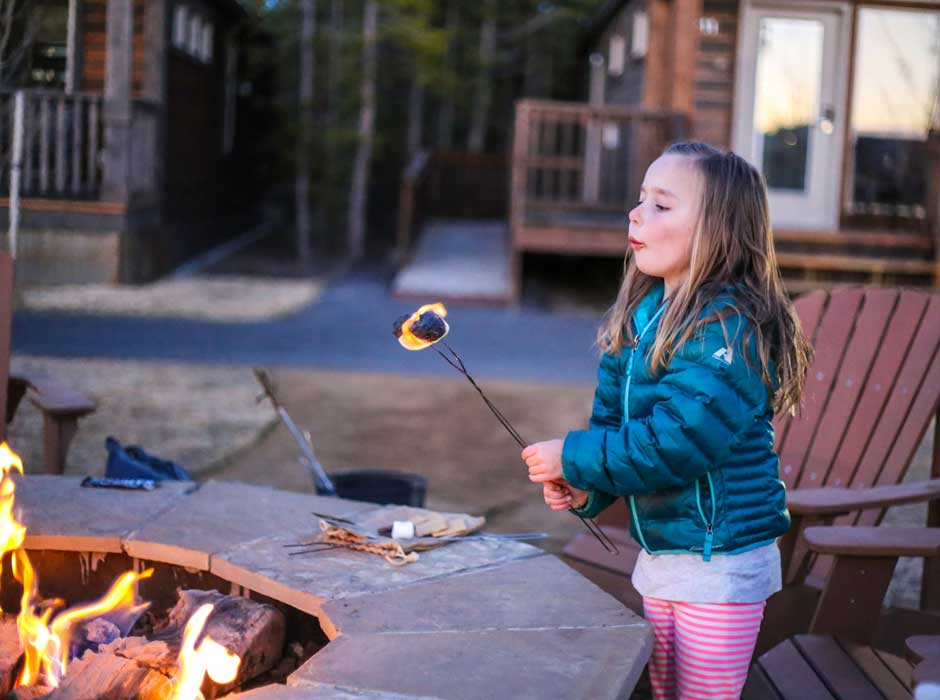 Little girl making S'mores at Explorer Cabins fire pits