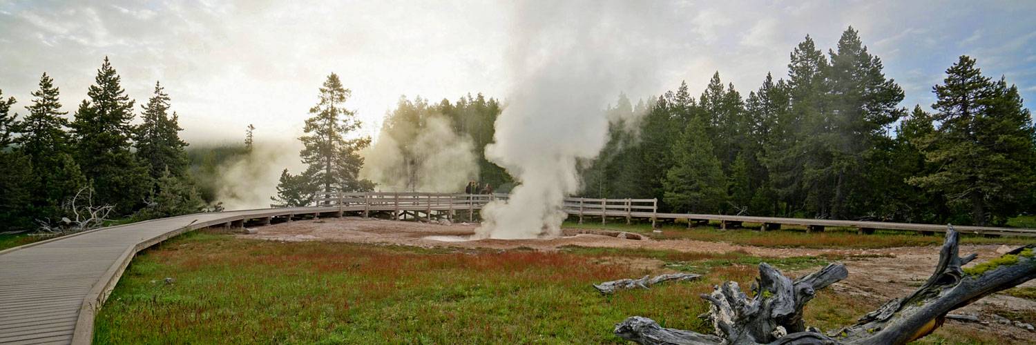 Yellowstone visitors exploring the boardwalk around a mud pot