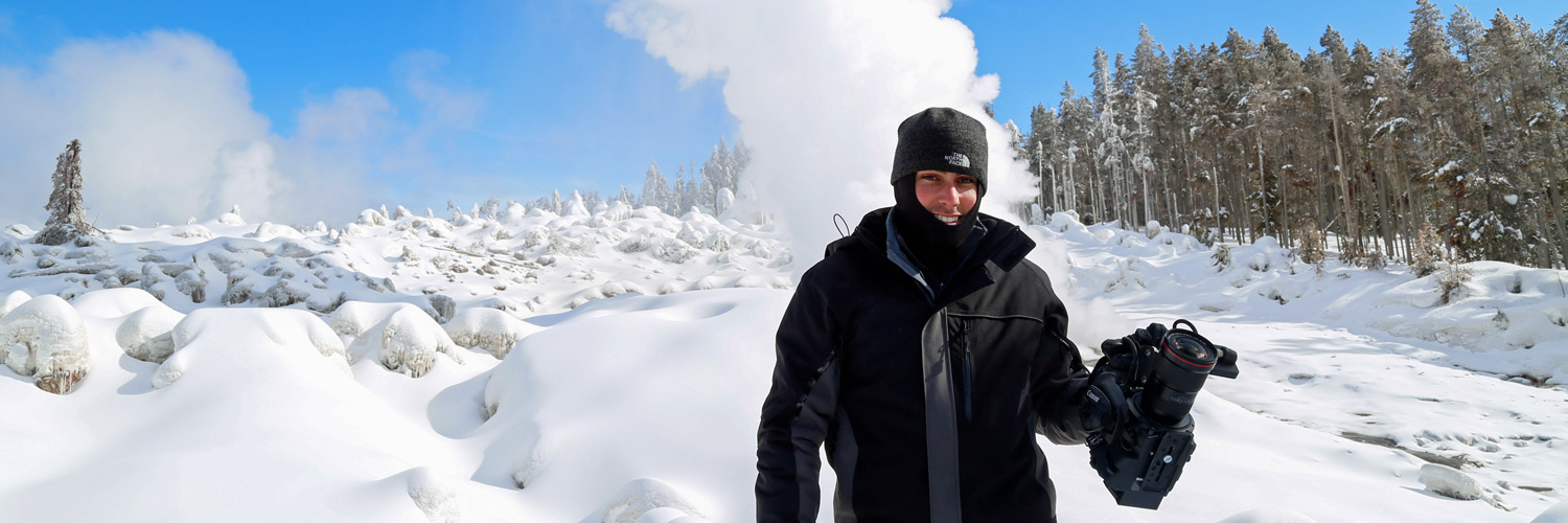 A photographer poses for a picture near a winter geyser in Yellowstone