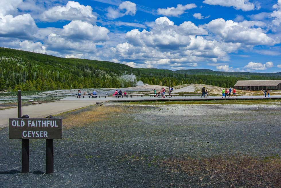 Old Faithful signage with people strolling behind