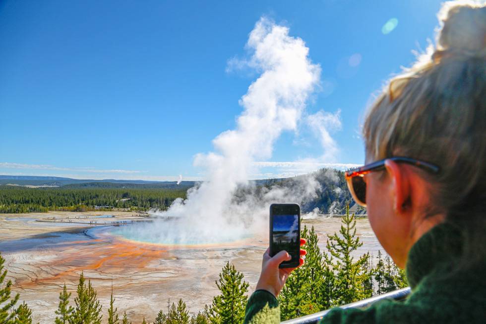 A Yellowstone visitor taking a cell photo of Grand Prismatic Spring