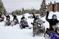 A happy group of Yellowstone snowmobilers waves as they ride off on their tour