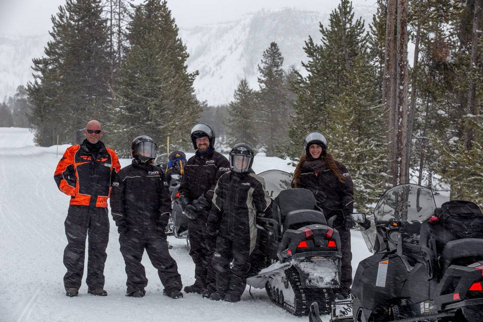 A Yellowstone snowmobiling group poses for a picture with their guide.