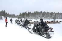 A snowmobile guide stops to teach his group about how Yellowstone bison forage in the winter.