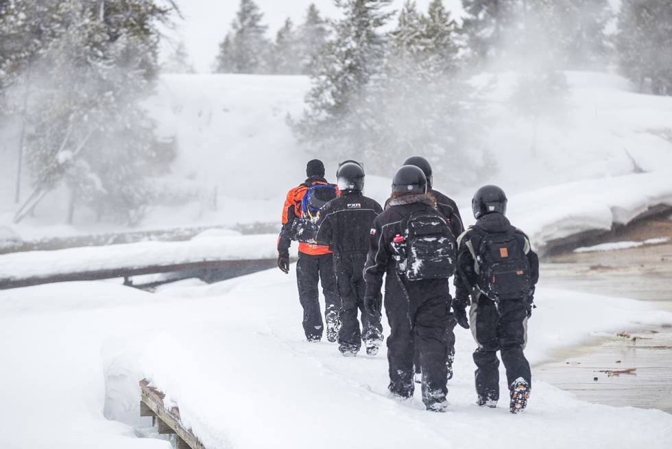 A snowmobile group stops at Midway Geyser Basin for a quick guided hike on the boardwalks.