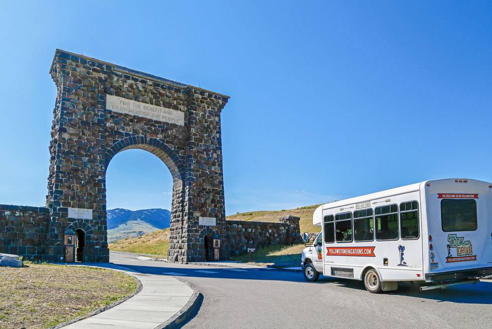 A Yellowstone Vacation Tours bus at the Roosevelt Arch
