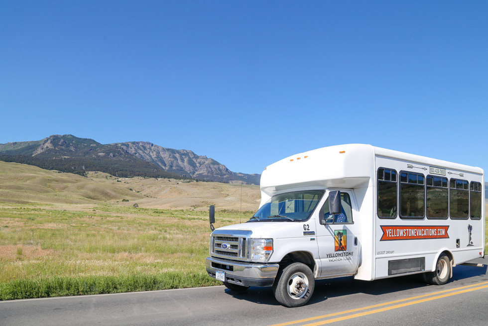 A Yellowstone Vacation Tours bus with classic Yellowstone mountain scenery